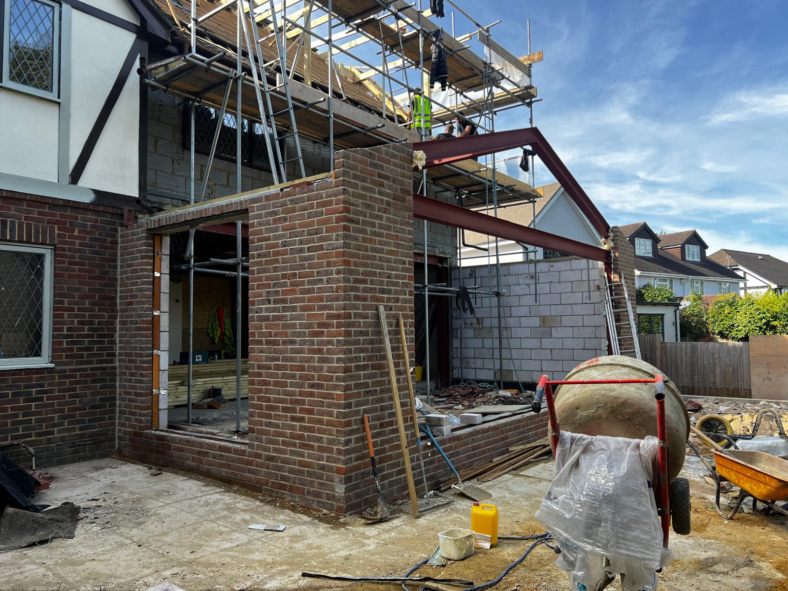 Brickwork in progress on rear extension with steel beams and cement mixer