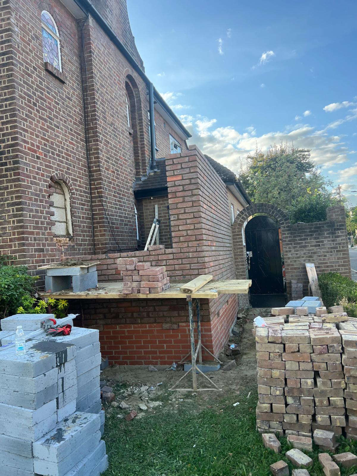 Red brick boundary wall with arched entrance in morning light