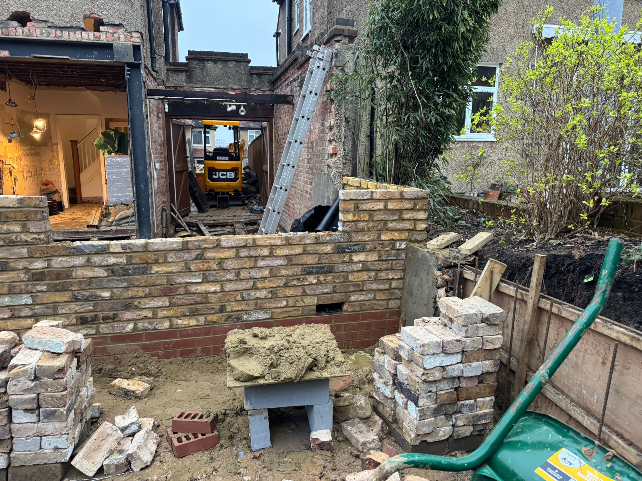 Garden extension in progress with JCB digger and brick boundary wall